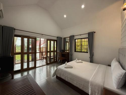 a bedroom with a white bed and a balcony at Alicia Resort in Koh Rong Island