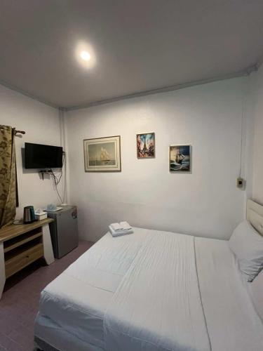 a bedroom with a white bed and a television at Hero Phuket in Nai Yang Beach