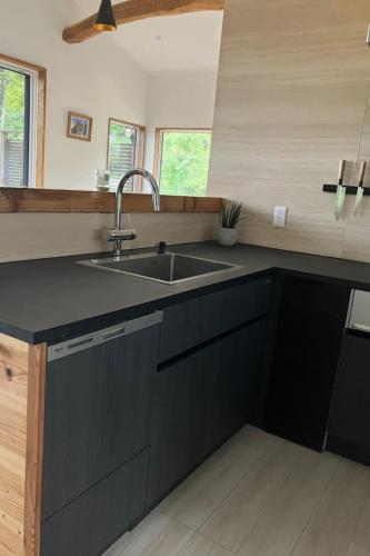 a kitchen with black cabinets and a sink at Chalet Tsugaike in Otari
