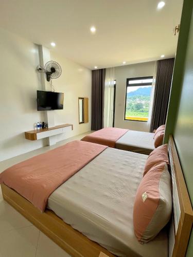 two beds in a hotel room with a window at Tít Mít HomeStay in Cao Bằng