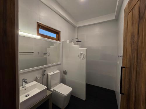 a white bathroom with a sink and a toilet at Villa Nutmeg Grove Galle in Galle