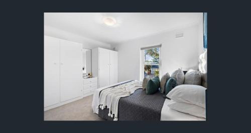 a bedroom with a bed with pillows and a window at Seaside Adelaide Holiday Apartment 2BR 1 min walk to Brighton Beach in Adelaide