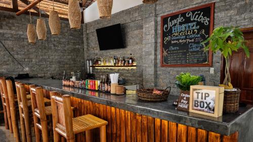 a bar with wooden chairs and a black counter at Jungle Vibes Hostel in San Juan