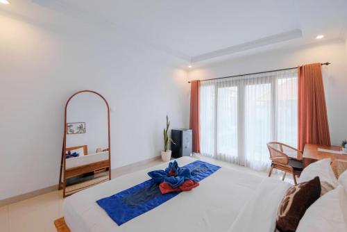 a bedroom with a white bed with a blue flower on it at Bali intan Canggu in Canggu