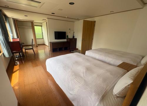 a hotel room with two beds and a television at ウェルカムイン松島 in Matsushima