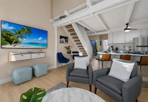 a living room with two chairs and a kitchen at Coral Cove-Poolside Condo and Panoramic Ocean View in Kahana
