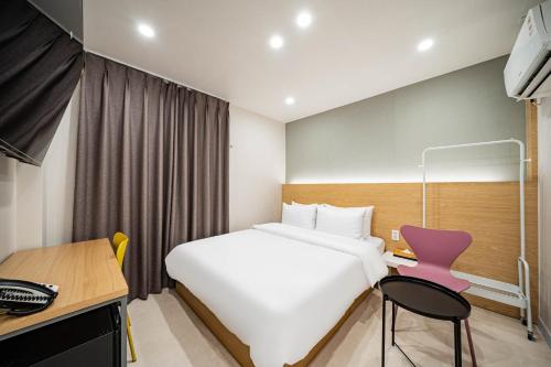 a bedroom with a white bed and a pink chair at Calm Rest Hotel Masan in Changwon