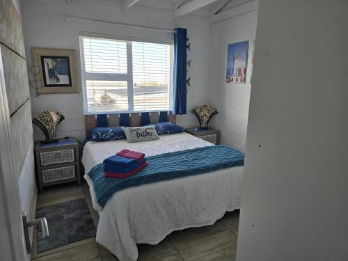 a bedroom with a bed with a blue blanket and a window at SONVANGER VILLA YZERFONTEIN in Yzerfontein