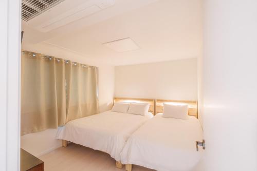 a bedroom with two beds with white sheets at Anguk House # Private 2F-3F Rooftop # Gyeongbokgung 1min # Bukchon in Seoul