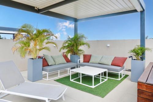 a patio with two couches and a table and palm trees at Villa Eden - 2 bedrooms with Private Rooftop Terrace & Pool, Ki Residences, Pereybère - KSN Collection Privée in Grand-Baie