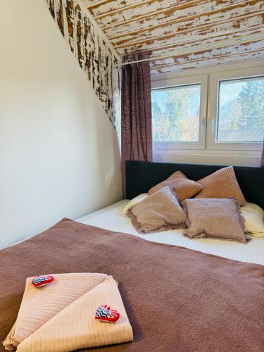 a bedroom with a bed with pillows and a window at Balcsitthon Apartmanok in Siófok