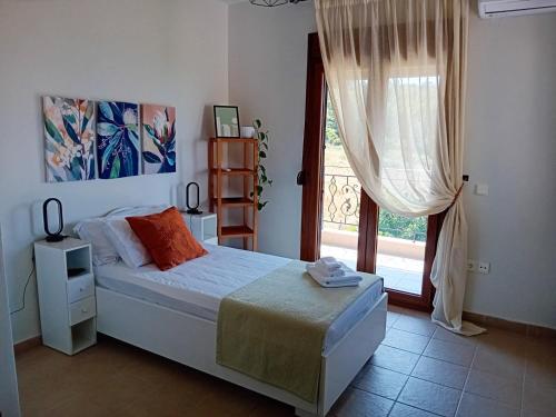 a bedroom with a bed and a large window at Κτήμα Verde in Agia Paraskevi