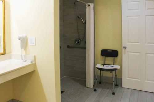 a bathroom with a shower with a chair in it at Rodeway Inn Medford South I-5 in Medford