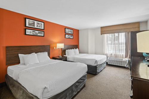 a hotel room with two beds and an orange wall at Sleep Inn Beaufort near MCAS in Beaufort