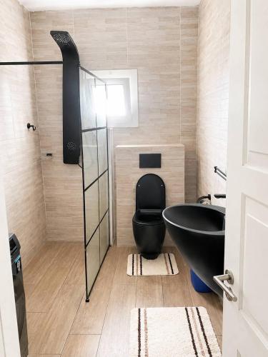 a bathroom with a black tub and a toilet at TchaoPremium in Lomé