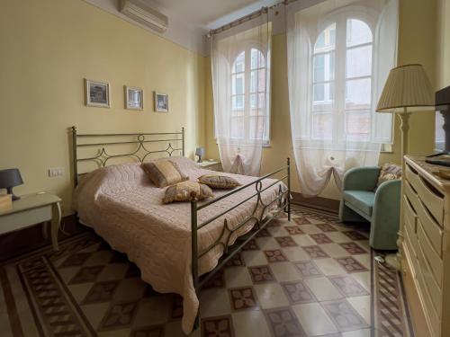 a bedroom with a bed and a chair and two windows at A Palazzo Busdraghi Residenza D'Epoca in Lucca