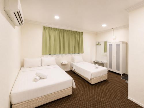 a hotel room with two beds and a window at Ridel Sunset Hotel in Kota Bharu