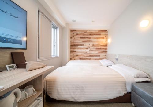 a bedroom with a large bed and a flat screen tv at Super Hotel Kushiro-Ekimae in Kushiro