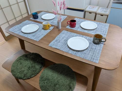 a wooden table with plates and mugs on it at 牟礼ぐらし宿 in Takamatsu