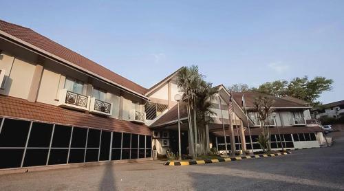 two buildings with palm trees in front of a street at Hotel Seri Malaysia Temerloh in Temerloh