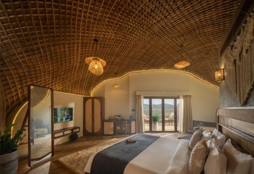a bedroom with a large bed with a wooden ceiling at Monticle Glamps in Vagamon