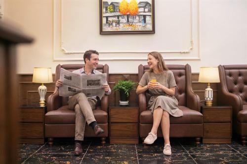 a man and a woman sitting in chairs in a waiting room at Bastra Classy Hotel in Hanoi