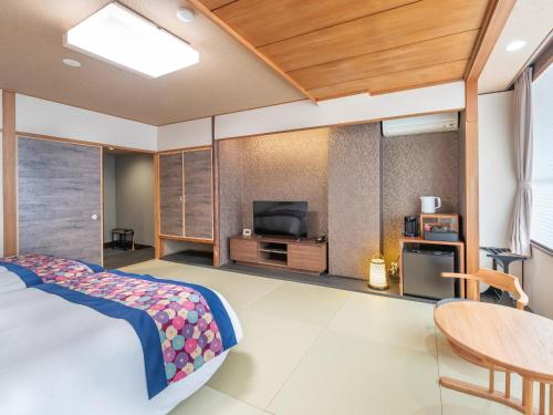 a bedroom with a bed and a flat screen tv at Subaruyado Yoshino in Tokushima