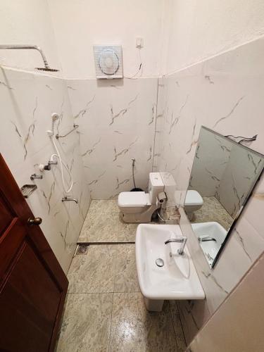 a bathroom with a sink and a toilet and a mirror at Baywatch Arugambay in Arugam Bay