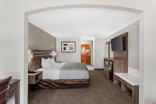 a hotel room with a bed and a flat screen tv at Quality Inn & Suites Beaumont in Beaumont