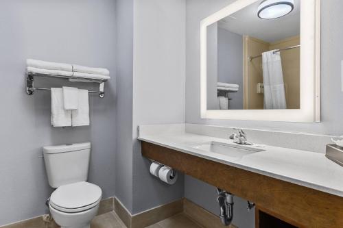 a bathroom with a toilet and a sink with a mirror at Comfort Inn & Suites Tyler North in Tyler