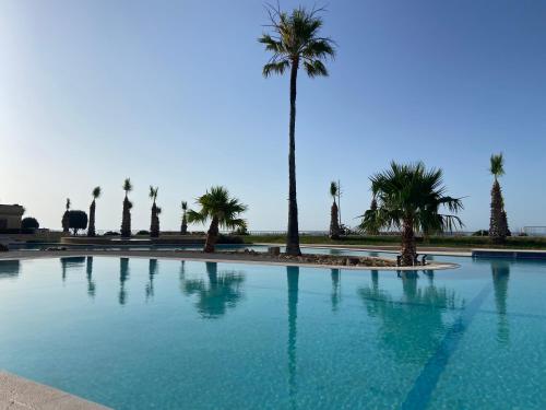 a large swimming pool with palm trees in the background at Fort Chambray, Blissful Escape in Għajnsielem