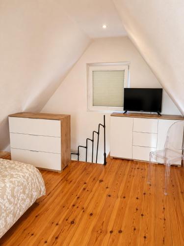 a bedroom with a bed and a television in a attic at Zacisze nad Jeziorem- prywatny domek blisko morza in Jezierzany