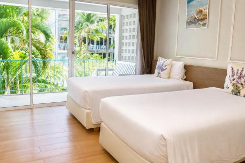 two beds in a hotel room with a balcony at Combo Beach Hotel Samui in Chaweng
