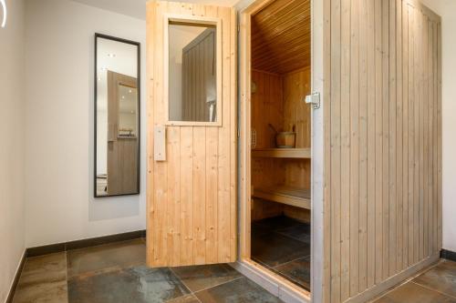 a wooden door in a room with a mirror at Gîte Perce Neige, Spa, Sauna in Gerbépal