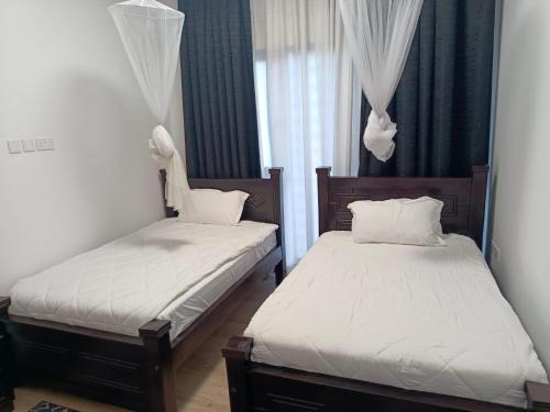 two beds in a small room with white sheets at Intercultural Apartment Nairobi Two Rivers in Nairobi