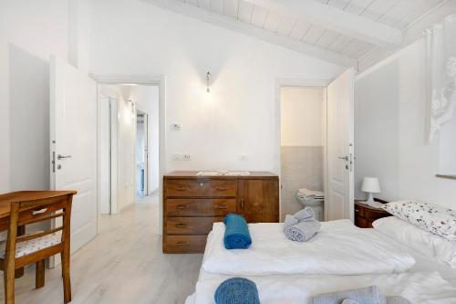 a white bedroom with two beds and a wooden dresser at Anika’s Home in Valfloriana