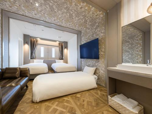a hotel room with two beds and a couch at Hotel Noir Blanc in Shizuoka