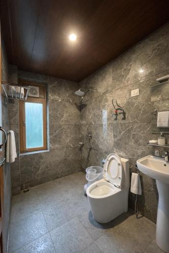 a bathroom with a toilet and a sink at Mountain Route Cottage in Manāli