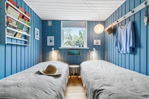 a bedroom with blue walls and a bed with a hat on it at 8528-Grenaa-Klitten-28 in Grenå