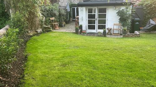 a yard with green grass and a white house at Garden View Homestay in Historic Patcham, Brighton in Brighton & Hove