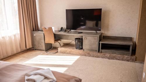 a room with a television and a desk with a chair at MenDan Magic Spa & Wellness Hotel in Zalakaros