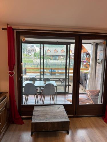 a dining room with a table and chairs and a large window at Chez Arthur et Léa in La Joue du Loup
