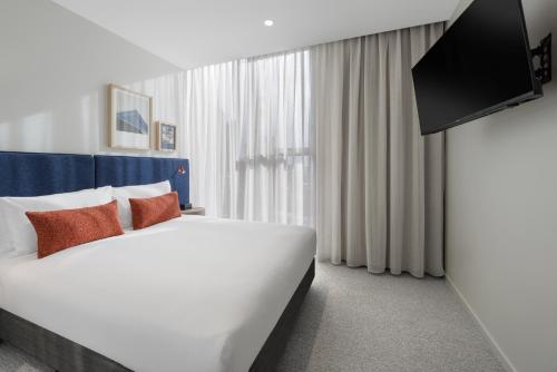 a hotel room with a large bed and a flat screen tv at Quest Southport in Gold Coast