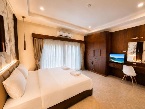 a bedroom with a white bed and a television at Phratamnak Seaside Pool Villa in Pattaya South