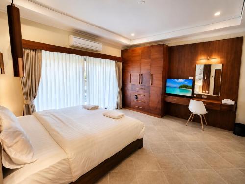 a bedroom with a large bed and a flat screen tv at Phratamnak Seaside Pool Villa in Pattaya South