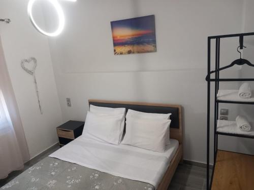 a bedroom with a bed with white sheets and a shelf at Coastal vista 2 in Neos Panteleimonas