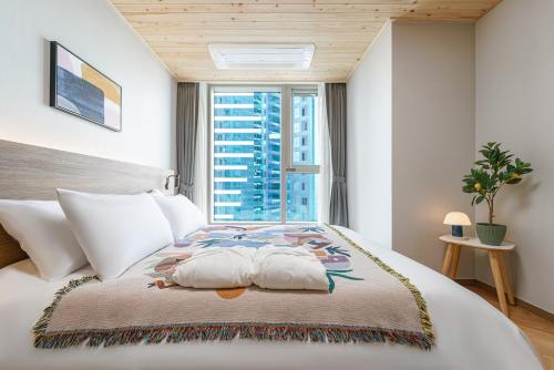 a bedroom with a large bed with a window at Le Collective Busan station in Busan
