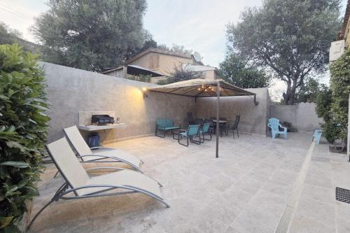 a patio with chairs and a table and an umbrella at CASA FOCI - maison T3 in Zonza