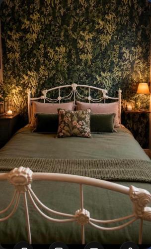 a bedroom with a bed with a canopy and floral wallpaper at Honeydon in Eaton Socon