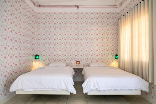two beds in a bedroom with pink wallpaper at Út Pink in Ấp Xuân Sơn